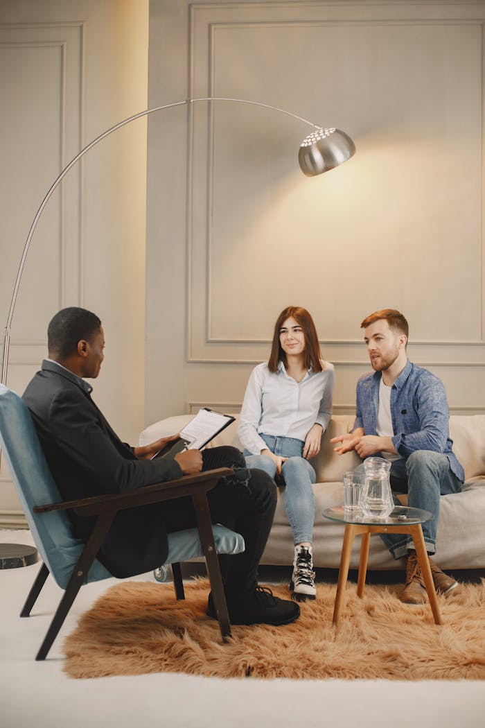 A couple having a discussion with a counselor in a modern room.